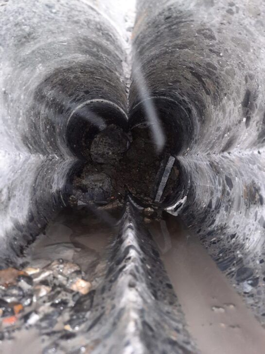 Tubería de túnel nevada con agua turbia y escombros en su interior.