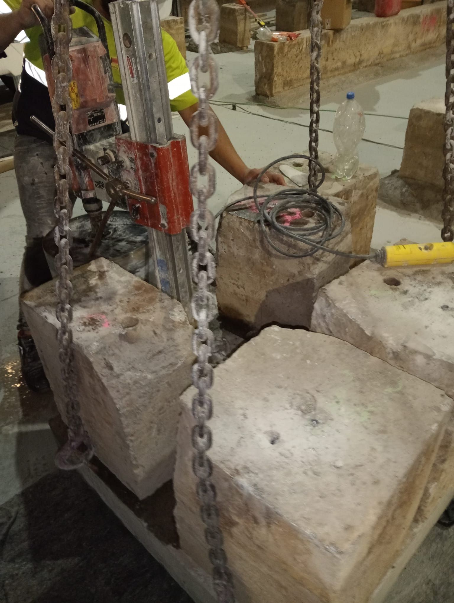 Obra en construcción con bloques de hormigón encadenados y herramientas en el suelo.