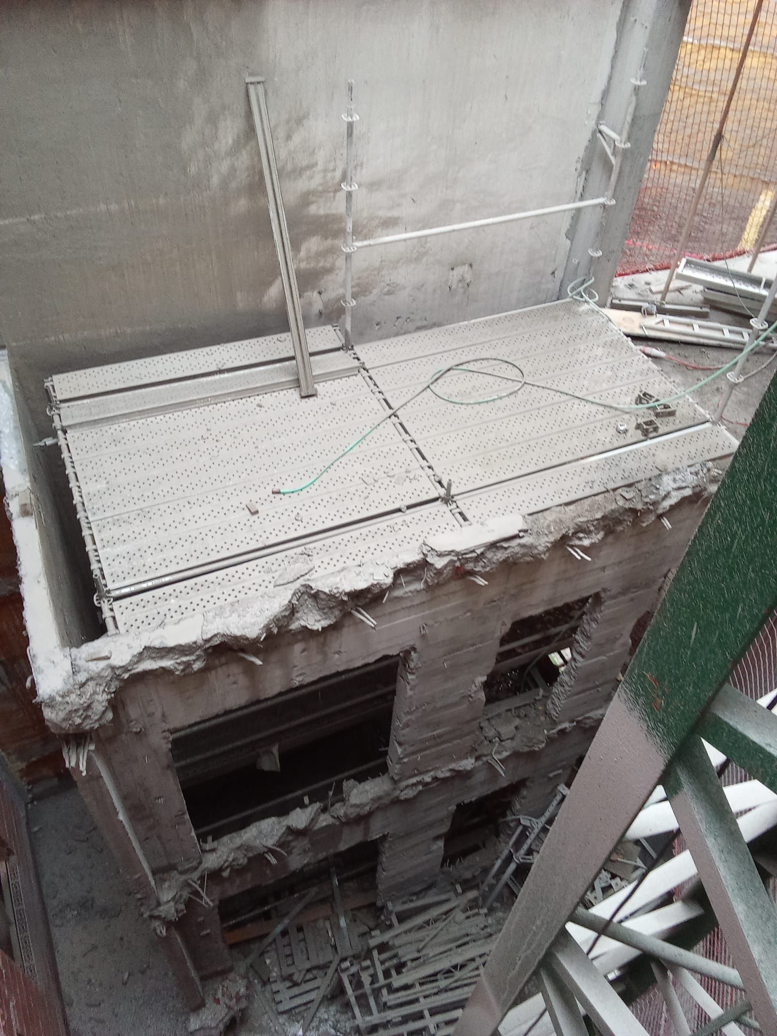 Azotea de hormigón cubierta de polvo de un edificio de gran altura en construcción, con andamios debajo.