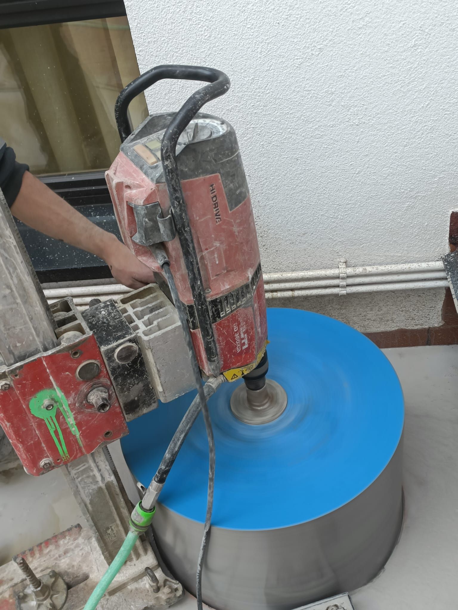 Esmerilado con herramienta eléctrica de un cilindro de metal azul y plateado sobre un banco de trabajo.