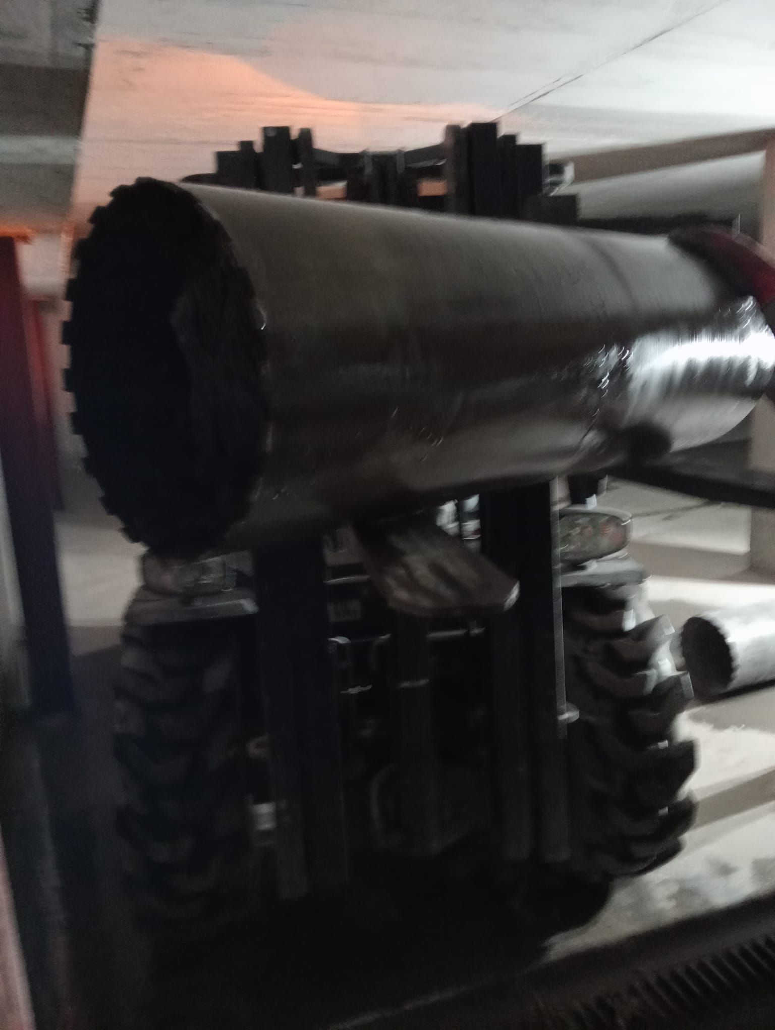 Gran tubo cilíndrico negro montado sobre una estructura metálica en un entorno industrial interior.