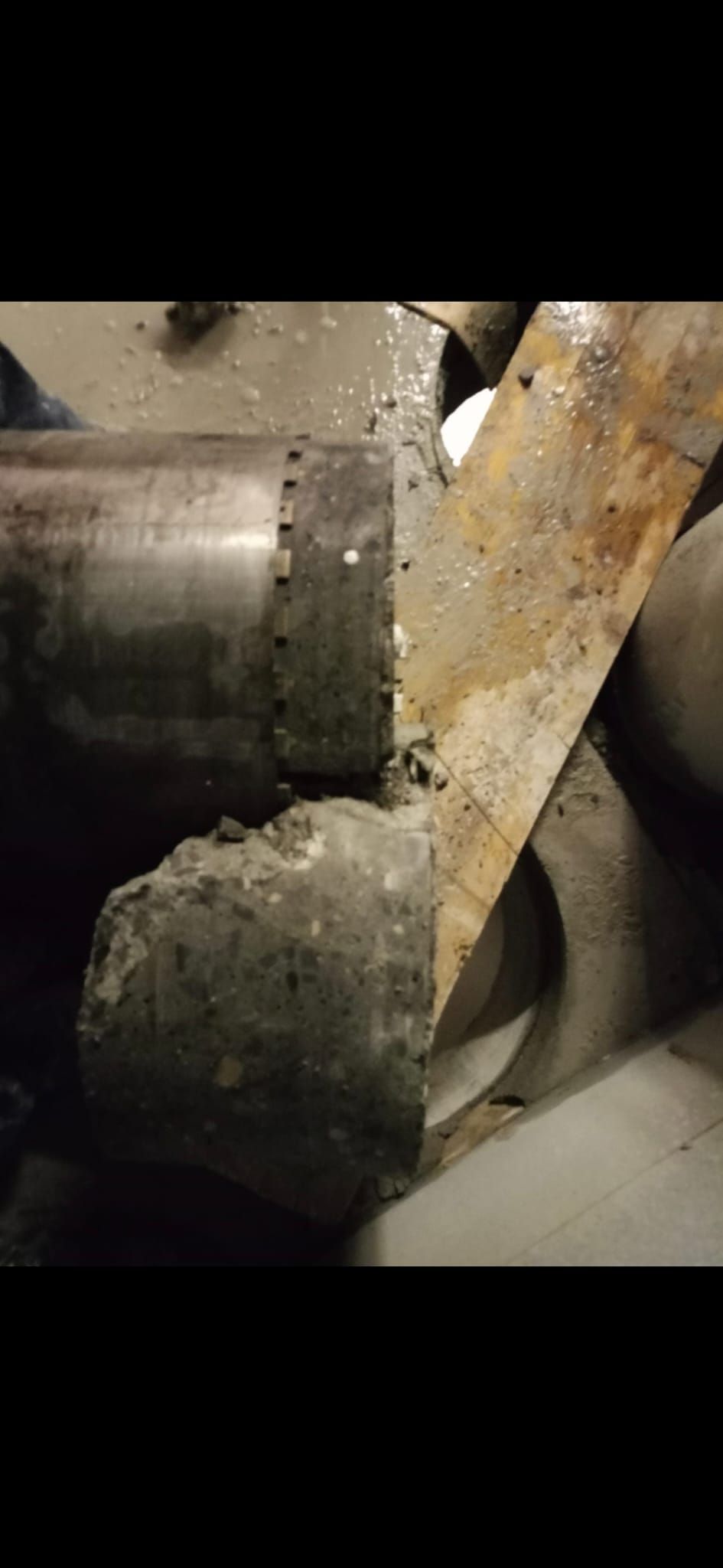 Primer plano de una tubería metálica polvorienta y un soporte angular oxidado en un entorno industrial.