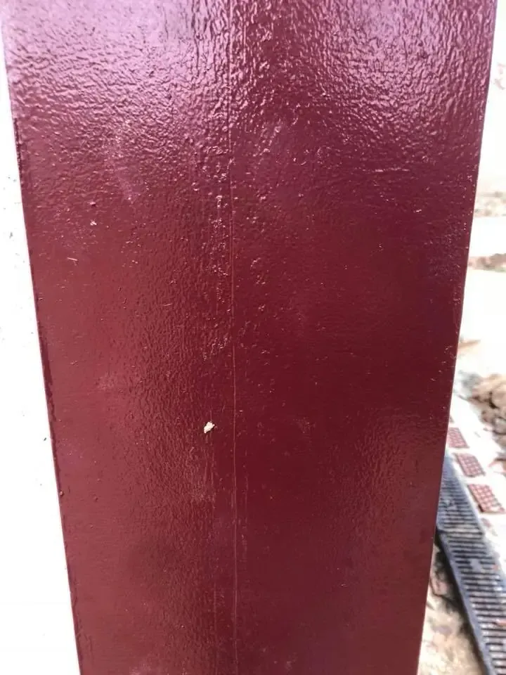 Pilar de madera pintado de rojo oscuro. Exterior.