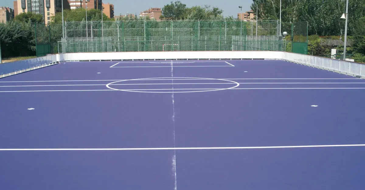 Cancha deportiva azul con lineas blancas y valla circundante.