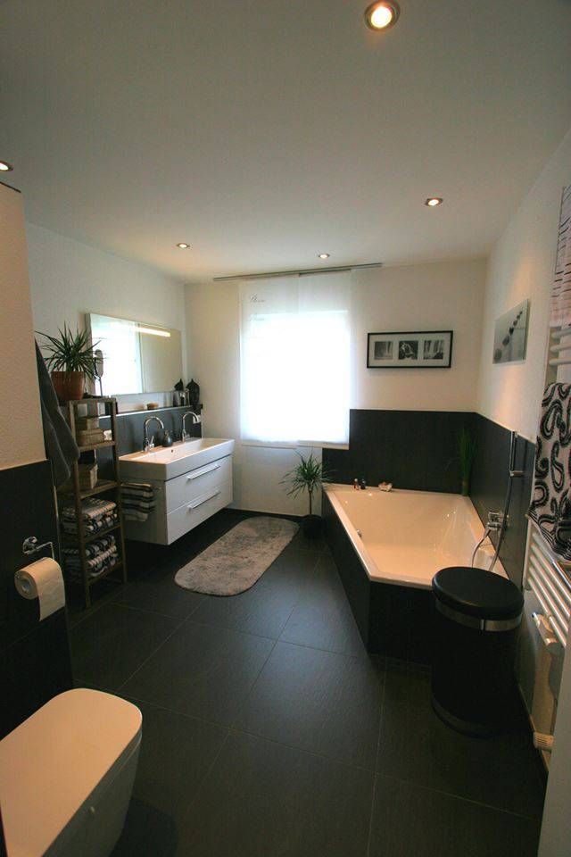 Dunkles Badezimmer mit asymmetrischer, eckiger Badewanne, Waschbecken und WC.