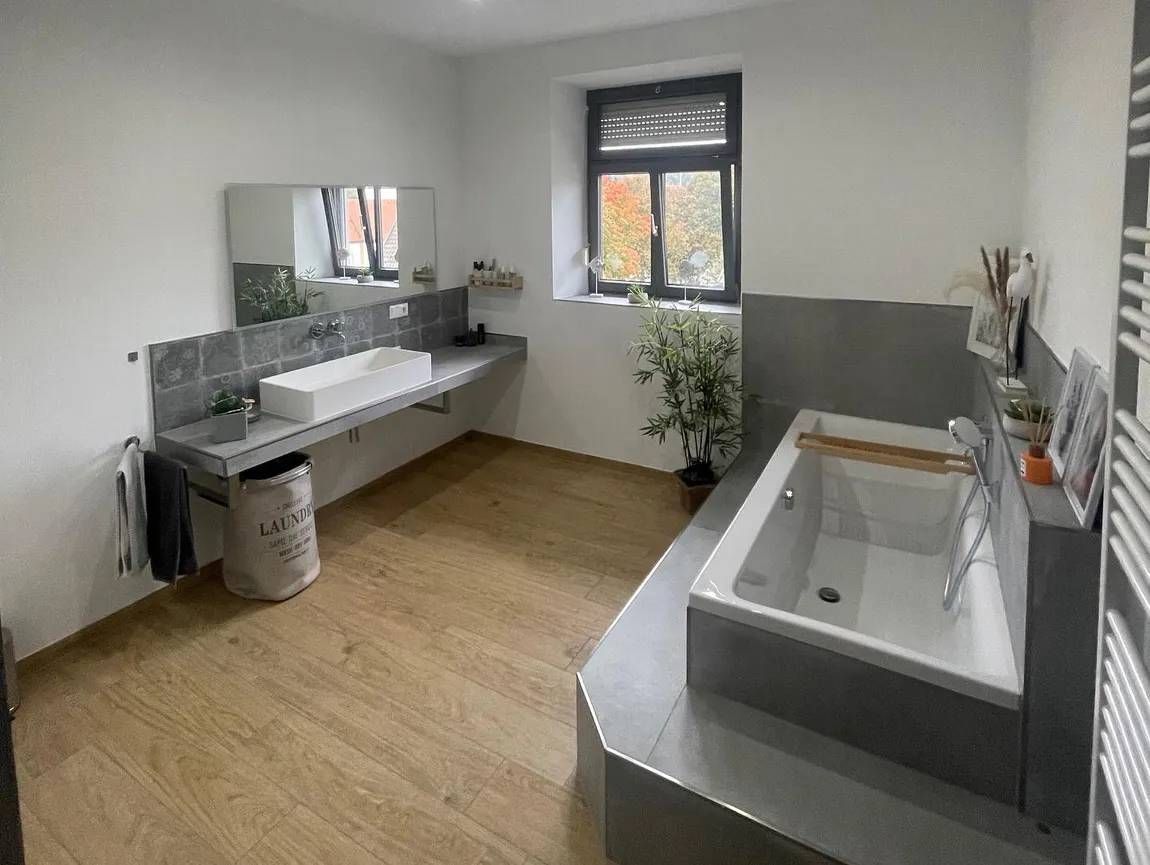 Grau geflieste Badewanne und Waschtisch, Bodenfliesen in Holzoptik