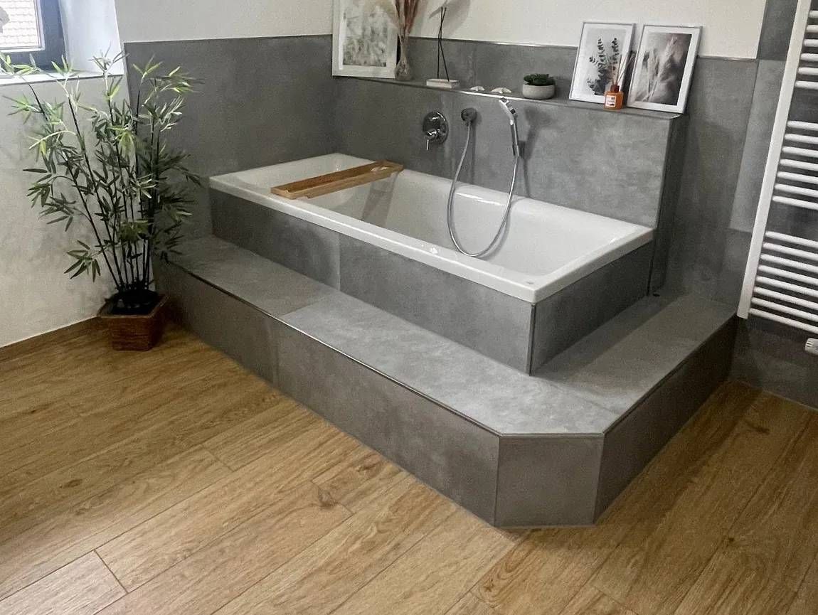 Grau geflieste Badewanne. Bodenfliesen in Holzoptik