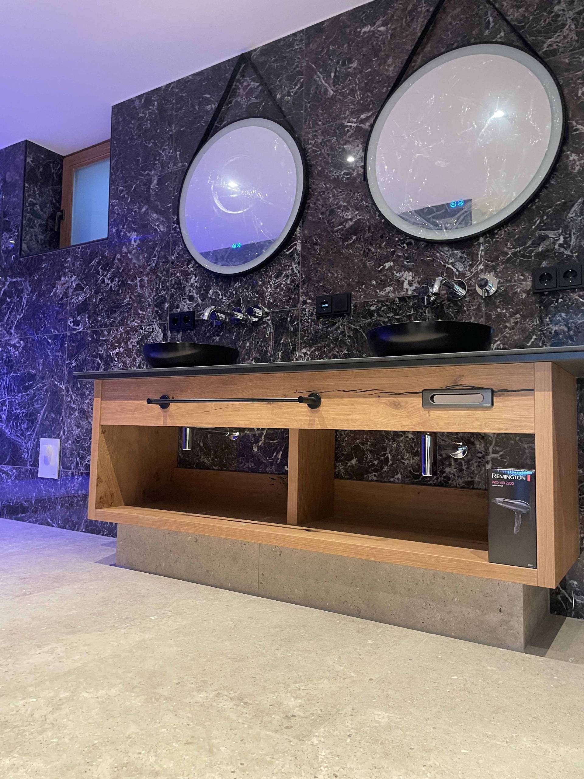 Dunkles Badezimmer mit grauen Fliesen auf dem Boden und Schwarz-Weiß marmorierte Fliesen an den Wänden