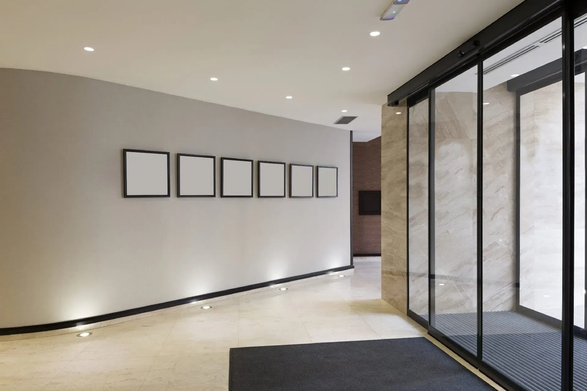Um longo corredor com uma porta de vidro deslizante e uma fileira de quadrados na parede.