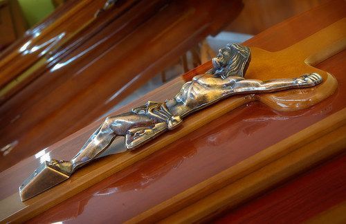 Una estatua de Jesús en una cruz encima de un ataúd de madera.