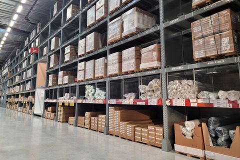 Lagerinnenraum mit Regalen, die mit Kisten und Waren gefüllt sind.