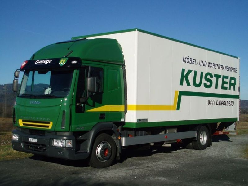 Green and white Kuster Möbel- und Warentransporte truck on a sunny day.