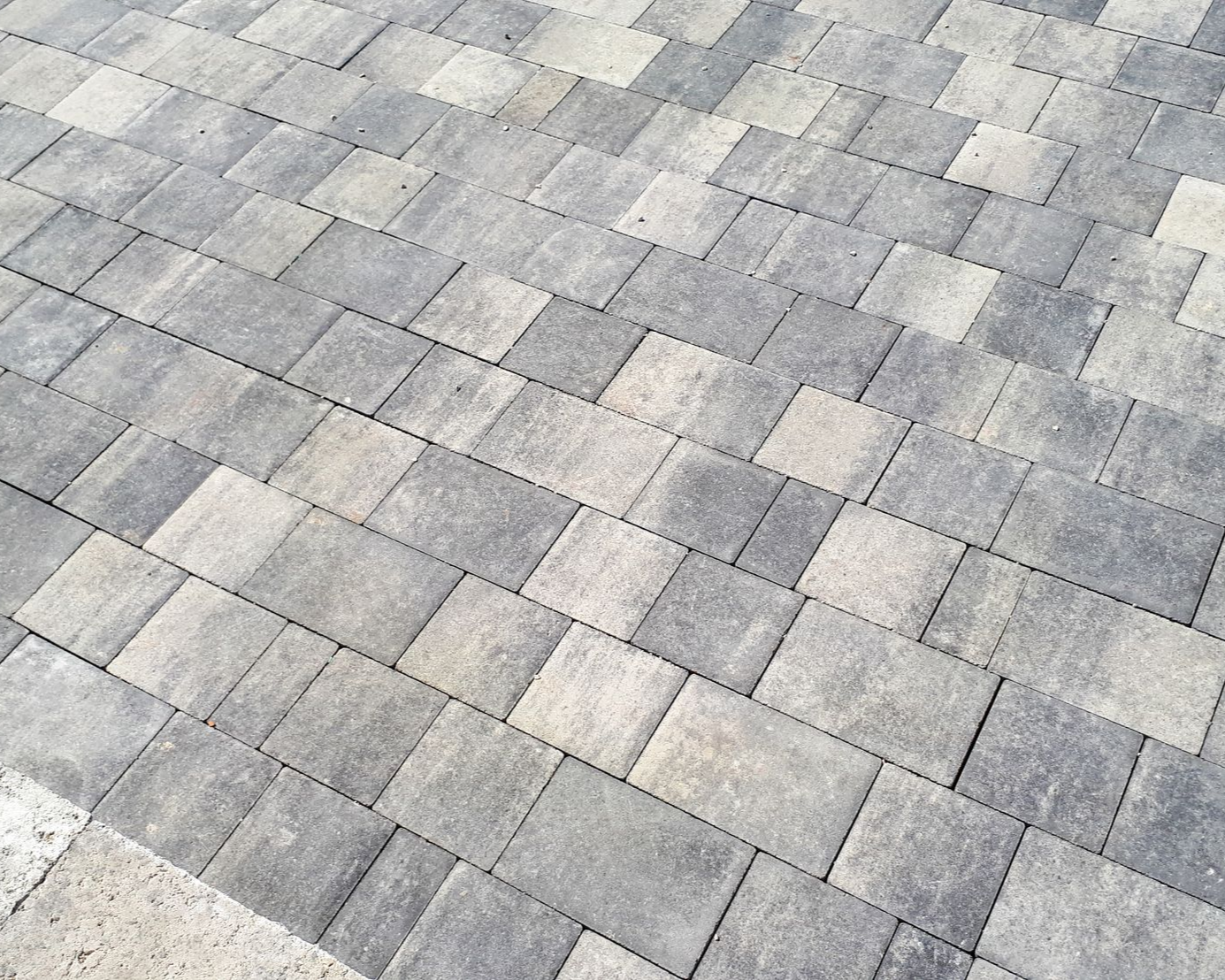 Pavés emboîtables gris et beiges disposés selon un motif géométrique.