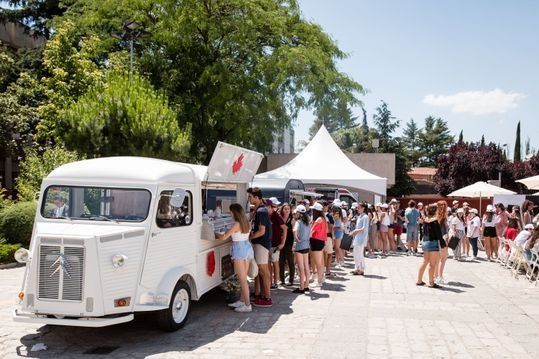 Un camión de comida blanco está estacionado frente a una multitud de personas.