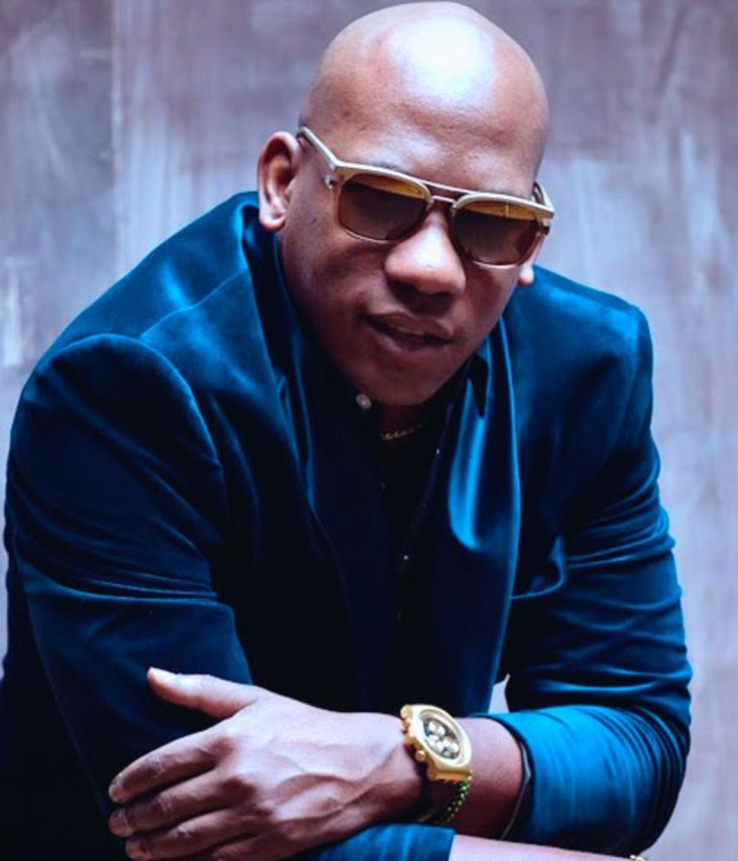 Un hombre calvo con gafas de sol y una chaqueta azul.