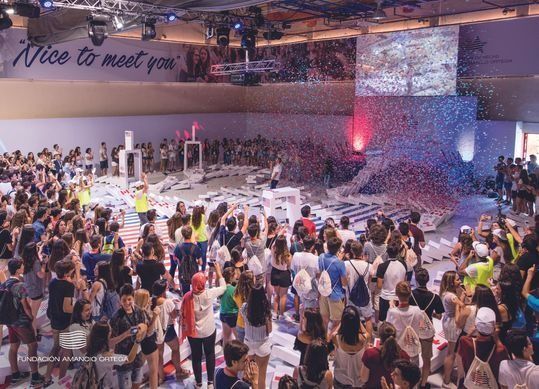 Una gran multitud de personas se reúne en una gran sala con un cartel que dice "encantado de conocerte"