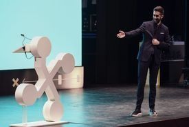 Un hombre con traje está de pie en un escenario dando una presentación.