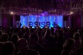 Una multitud de personas está sentada frente a un escenario en un concierto.