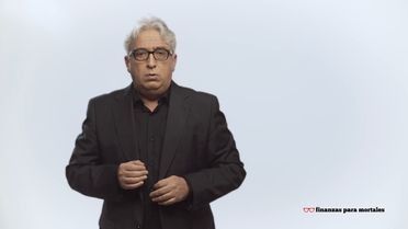 Un hombre con traje y gafas está de pie frente a un fondo blanco.