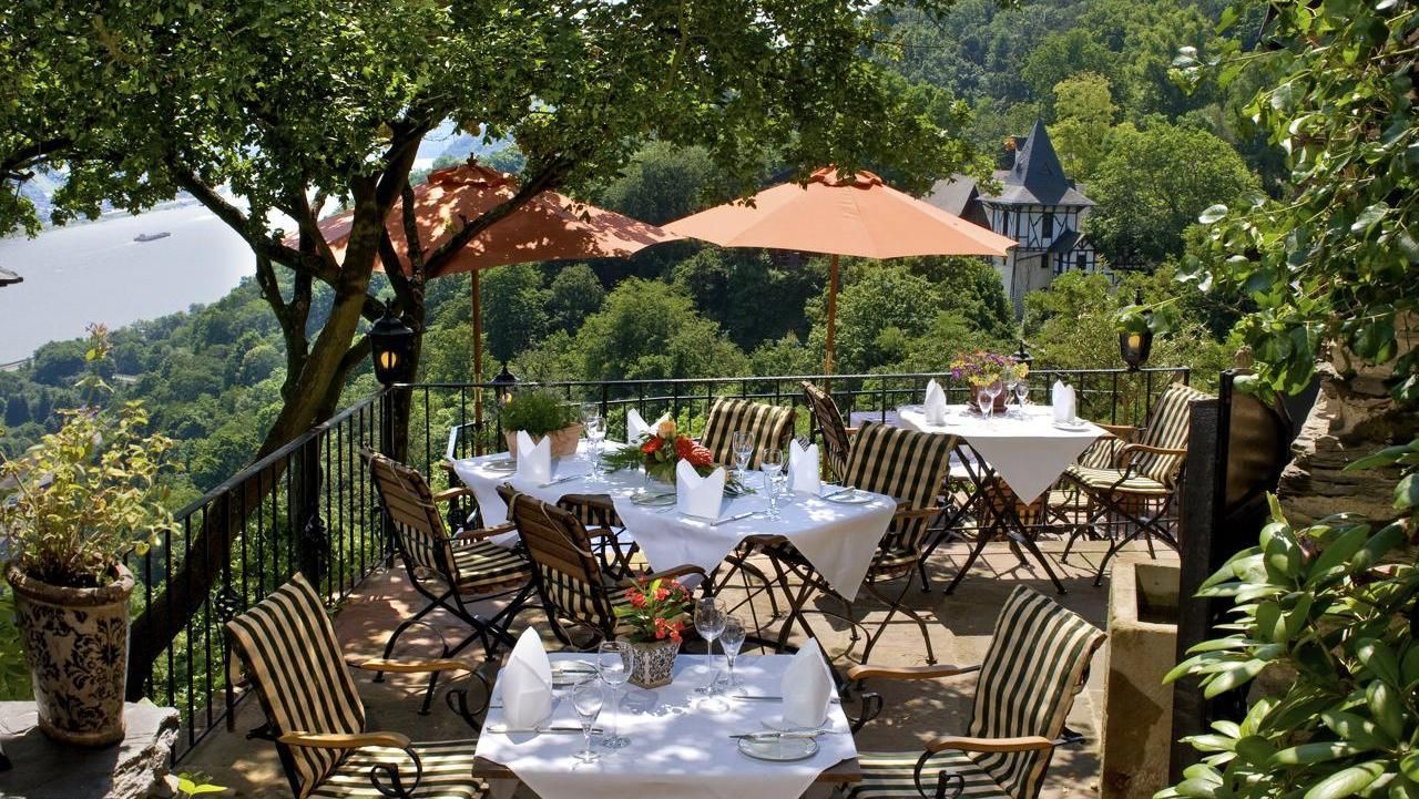 A patio with tables and chairs and umbrellas overlooking a river