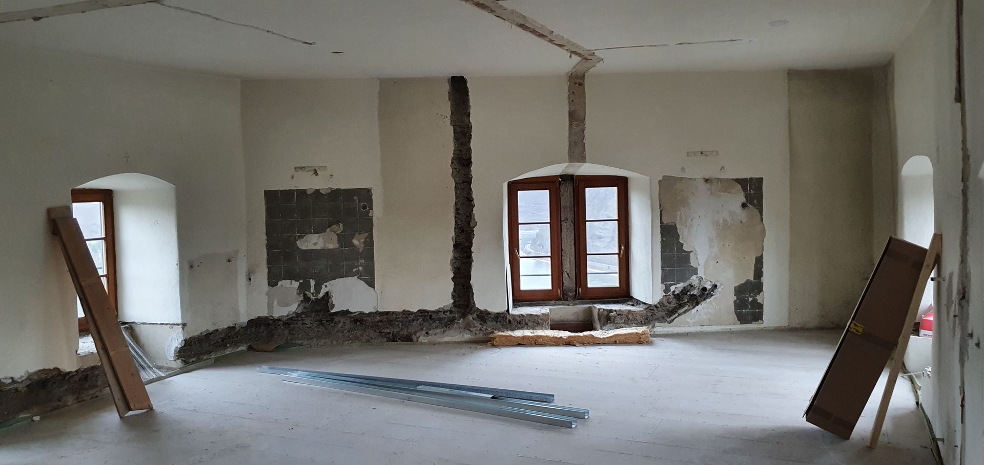 Ein großer Raum mit vielen Fenstern und ein paar Holzstücken auf dem Boden.