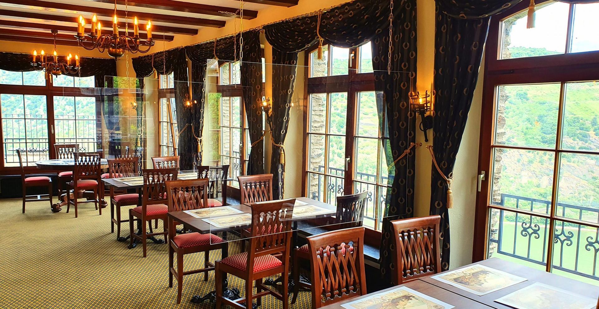 Ein Raum im Bistro der Schönburg mit Tischen und Stühlen und vielen Fenstern