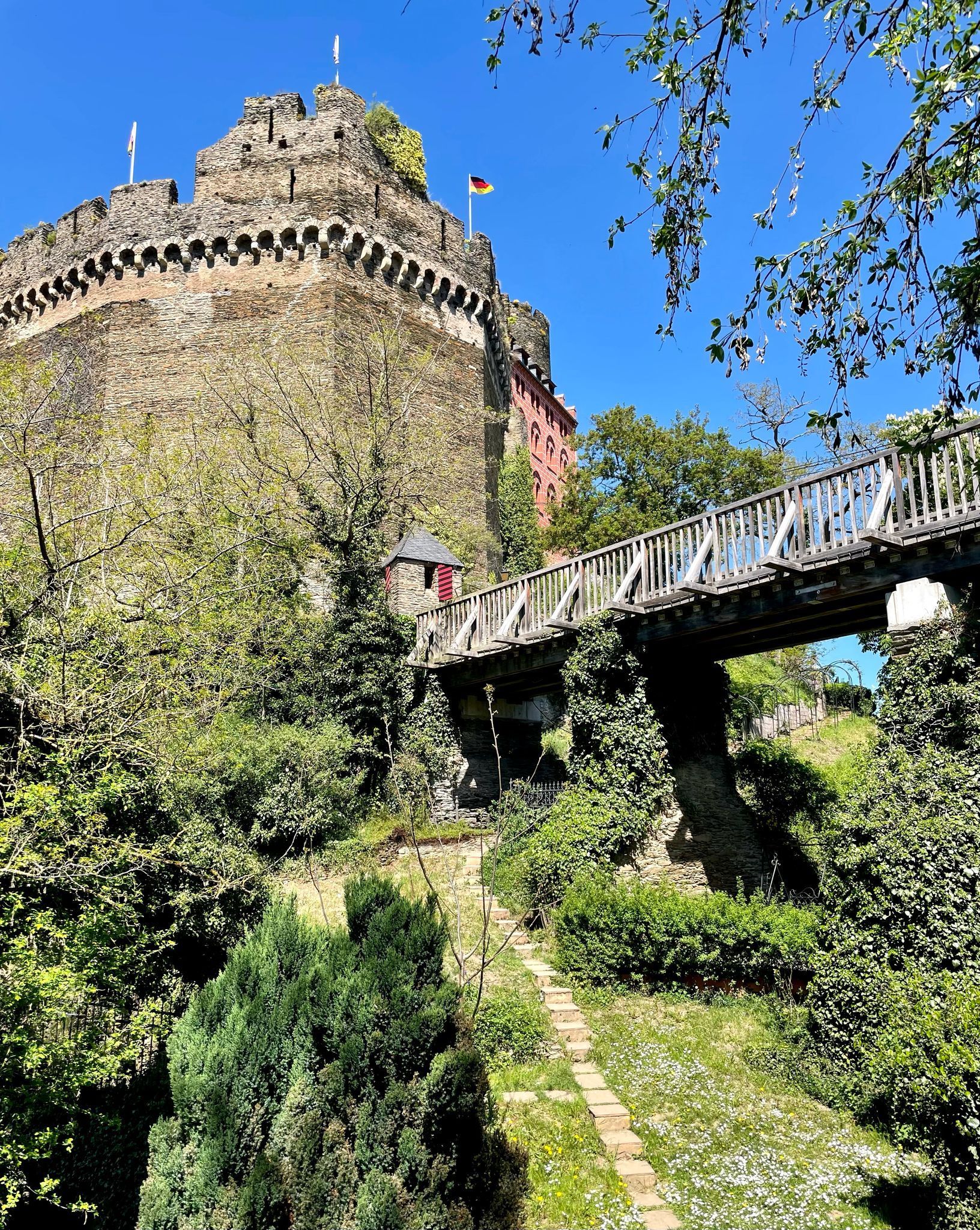 Eine Brücke, die zu einer Burg auf einem von Bäumen umgebenen Hügel führt.