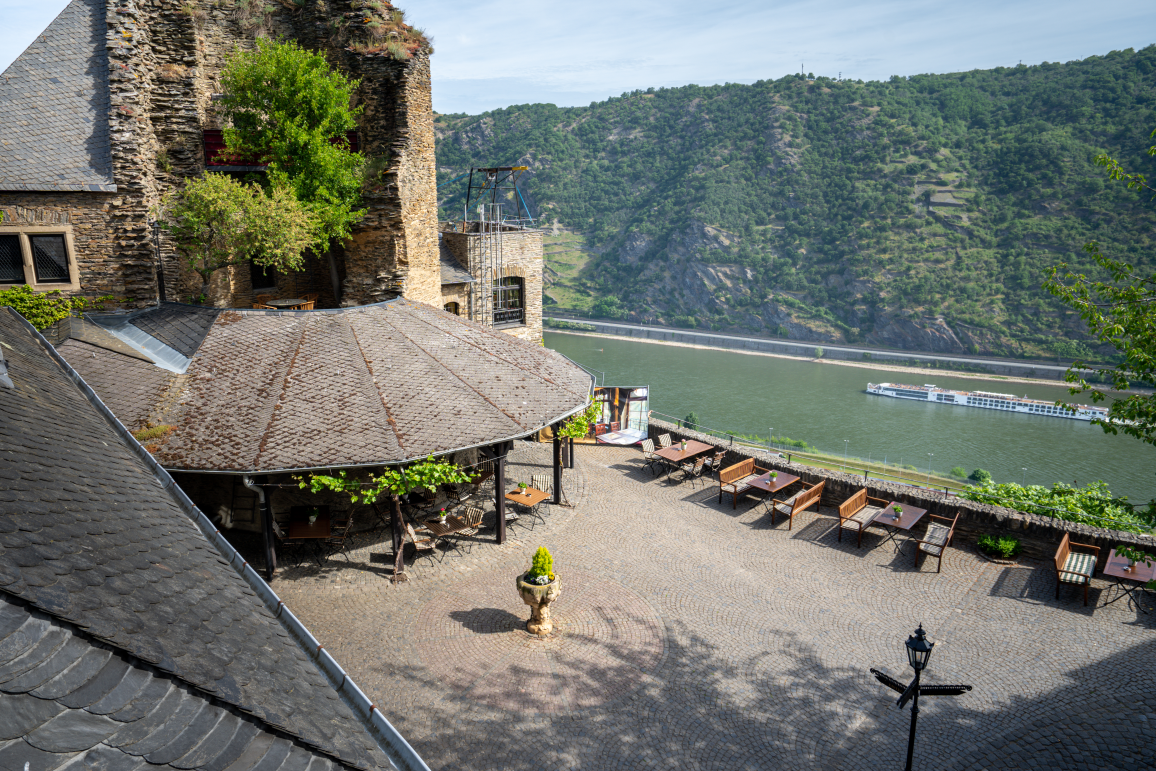 Innenhof mit Sitzgelegenheiten und Blick auf Fluss und Hügel. 