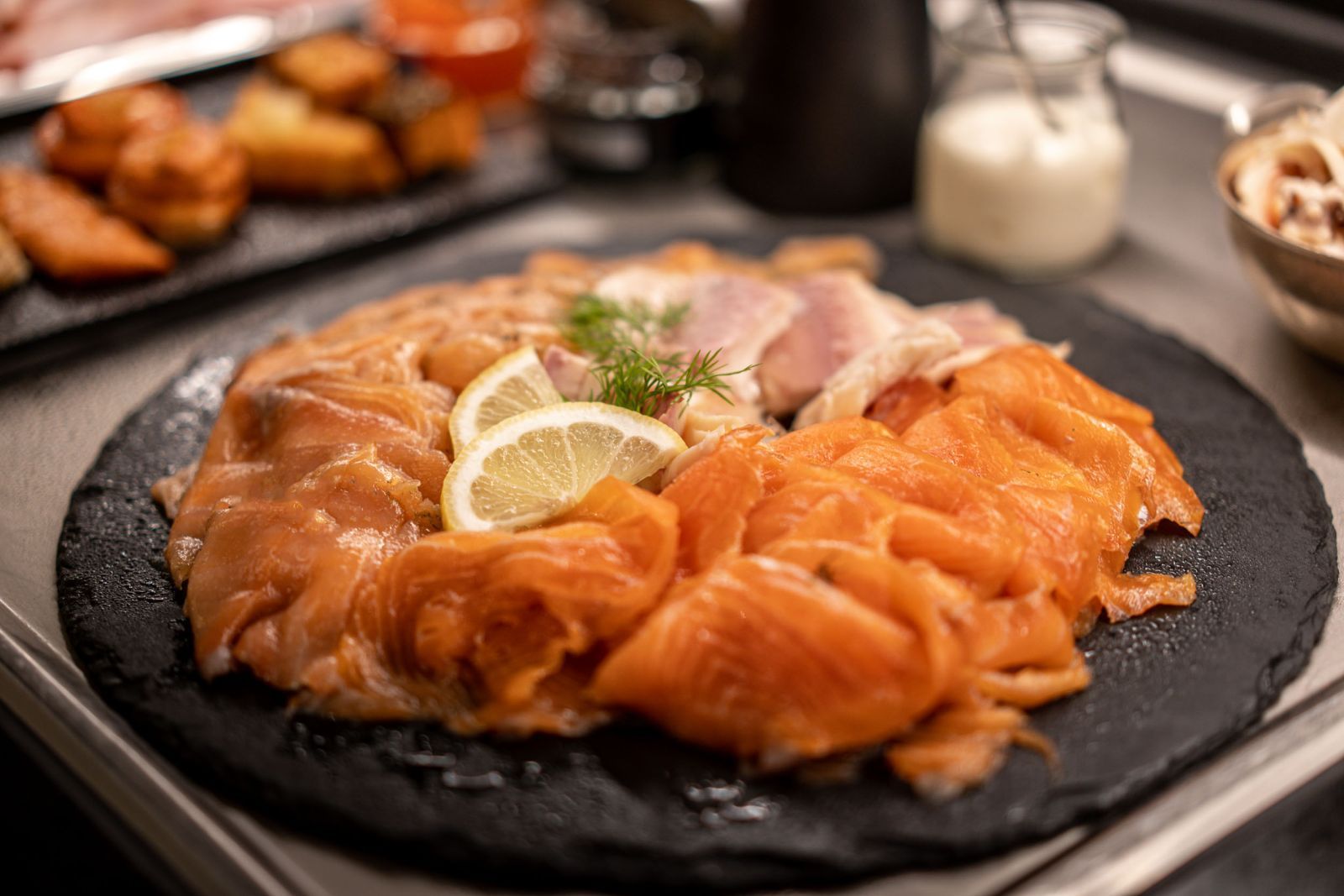 Ein Teller mit geräuchertem Lachs und Zitronenscheiben auf einem Tisch.