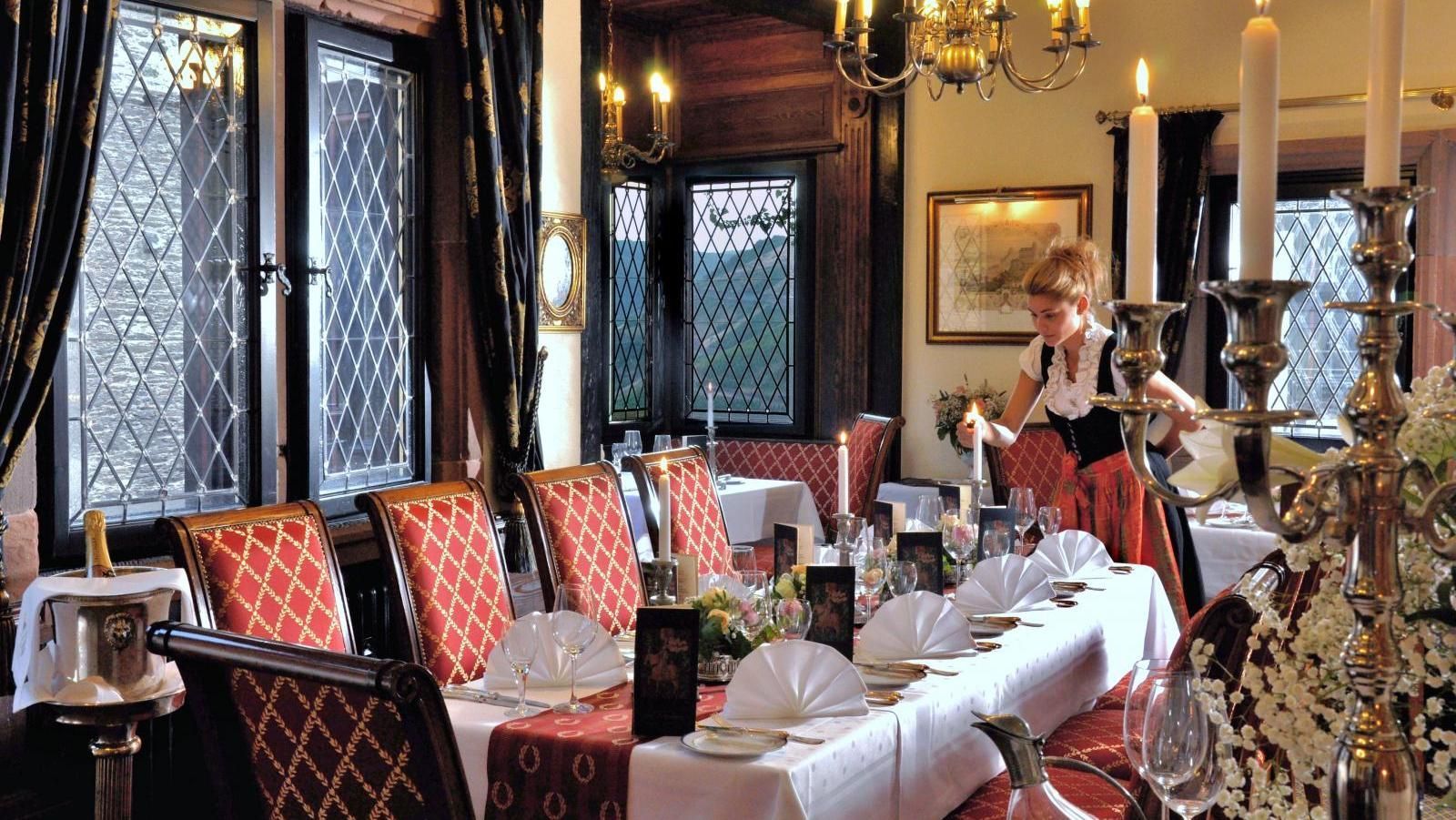 Eine Frau in einem roten Kleid steht vor einem langen Tisch in einem Restaurant.