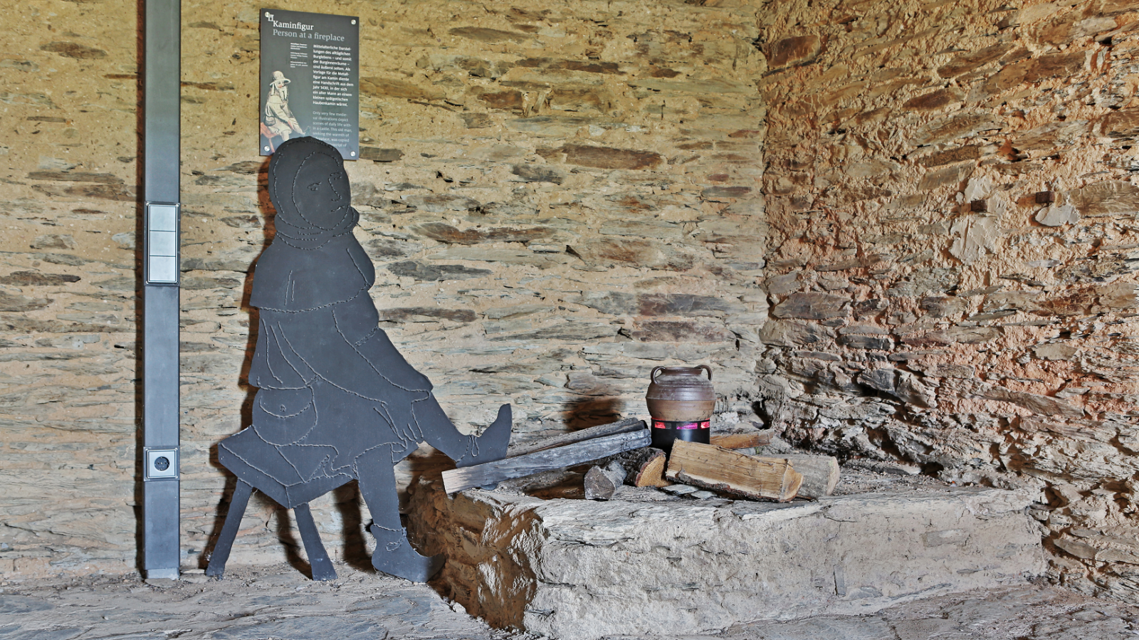 Die Silhouette einer Person, die auf einer Bank vor einer Steinmauer sitzt im Turmmuseum