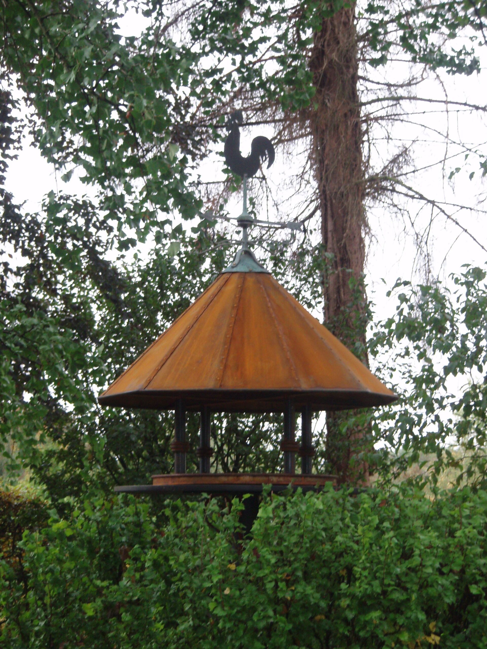 Hahn aus Metall auf Häuschen