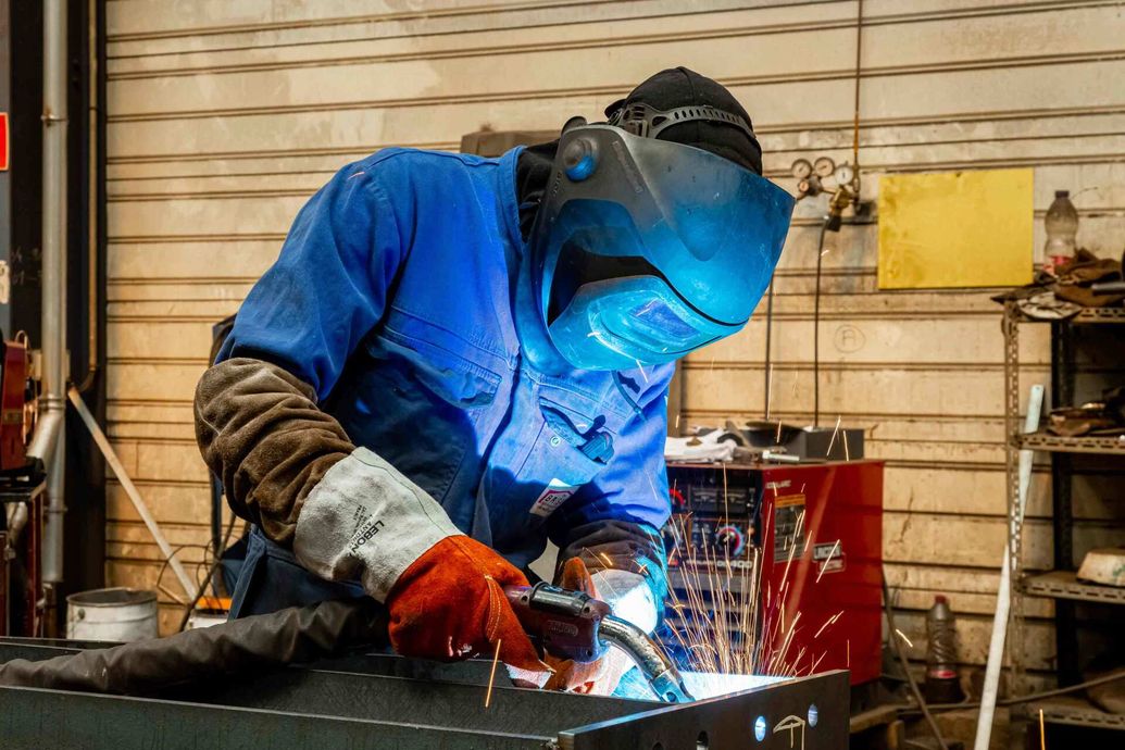 Homme en tenue de travail qui travaille du métal avec un outil  émettant des étincelles