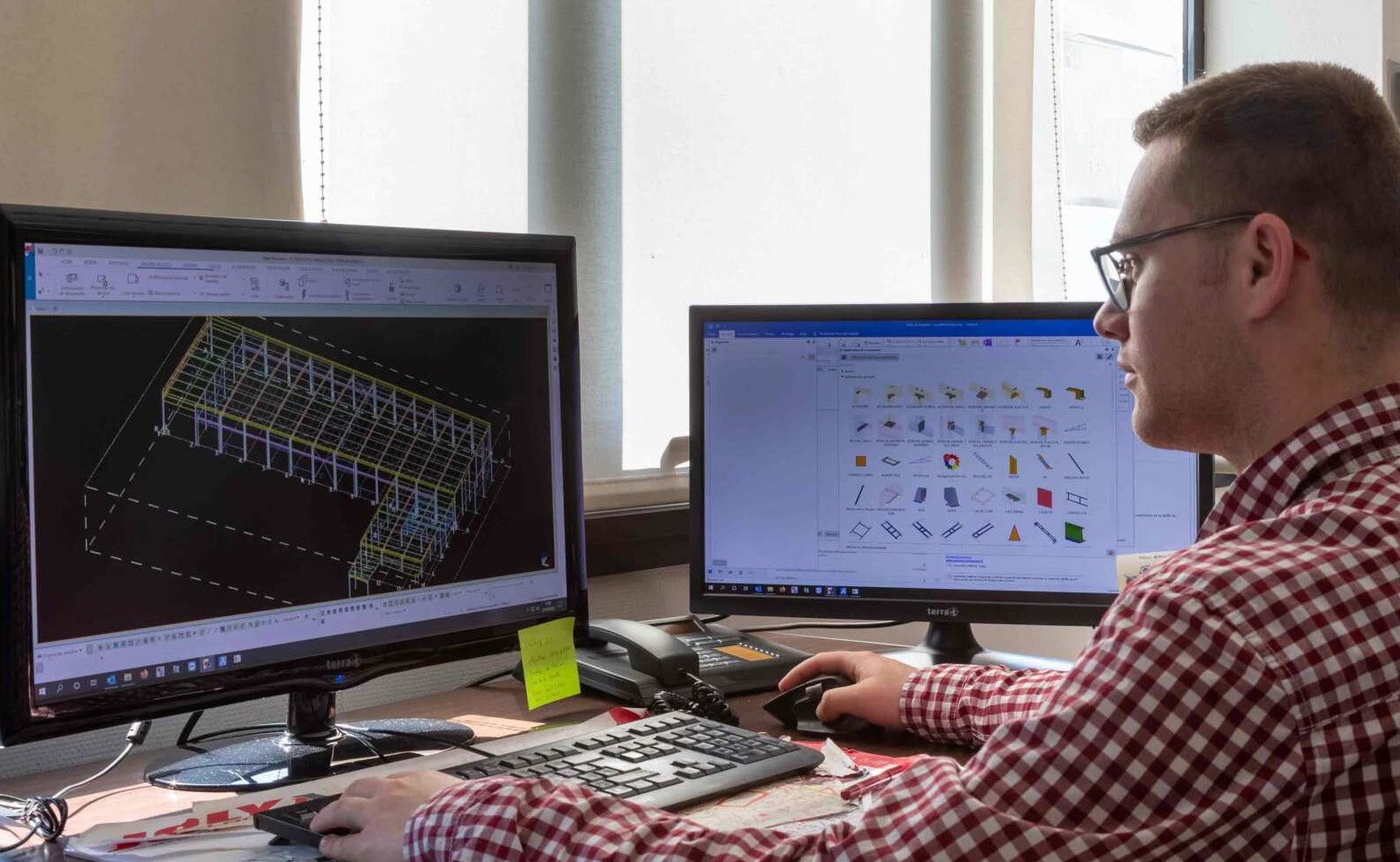 Homme qui designe des architectures sur deux écrans d'ordinateur