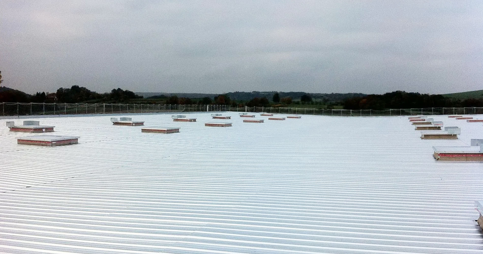 Toiture de bâtiment commercial avec revêtement en tôle et puit de lumière