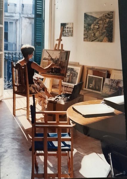 Dos pinceles sobre una paleta de artista salpicada de pintura de colores mezclados y un agujero en un vaso de pintura amarilla.