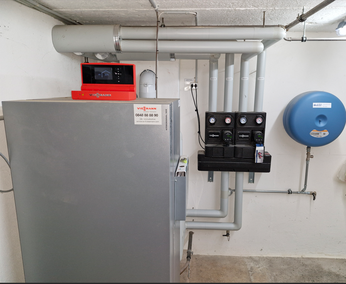 Eine Reihe Kupferrohre sind an einer Backsteinmauer aufgereiht. Sollberger & Co. AG