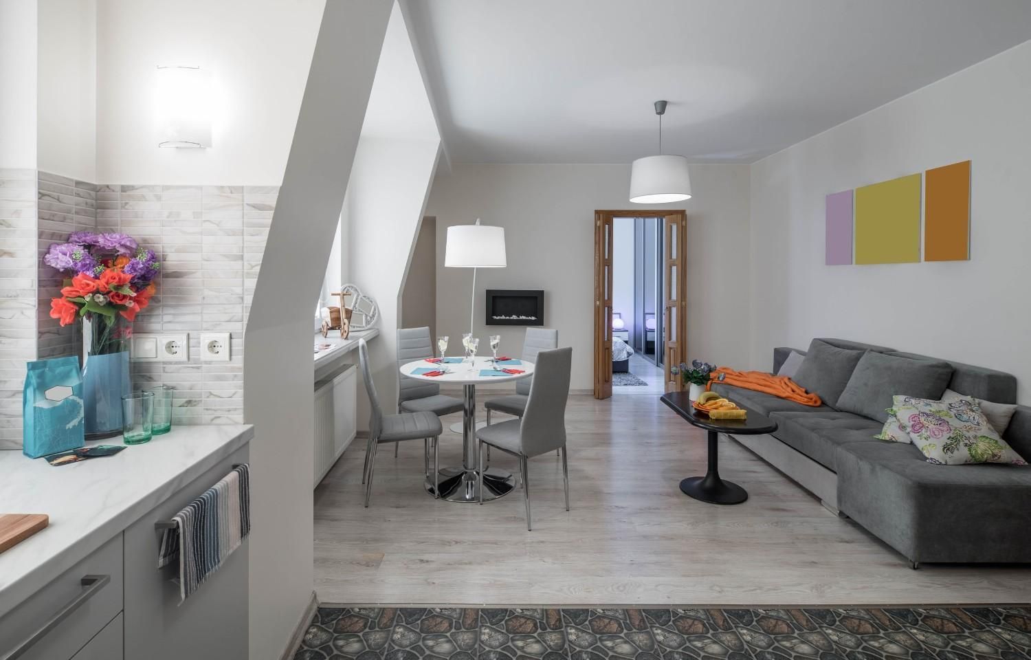 Moderna sala de estar y comedor de planta abierta con sofá gris, mesa y encimera de cocina a la izquierda.