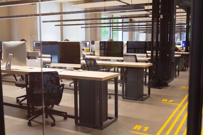 Oficina vacía con filas de escritorios, monitores de ordenador y sillas con ruedas en un espacio de trabajo moderno.