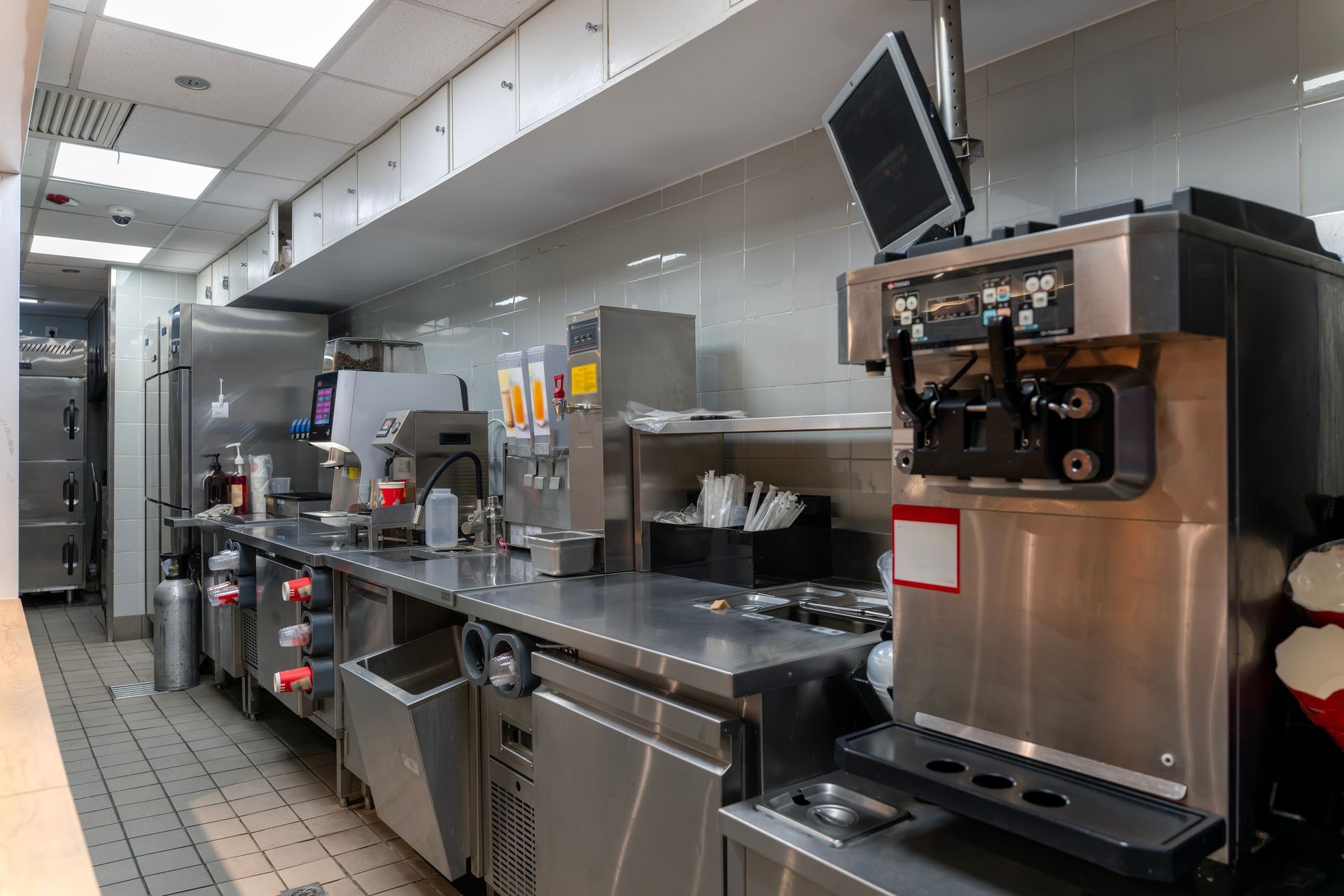 Un poste de cuisine commerciale en acier inoxydable avec une machine à glace à l'italienne, des comptoirs et divers ustensiles de préparation alimentaire.