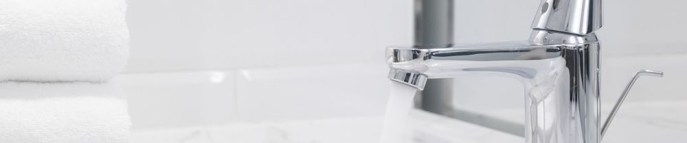 Un primer plano de un grifo con agua saliendo de él en un baño.
