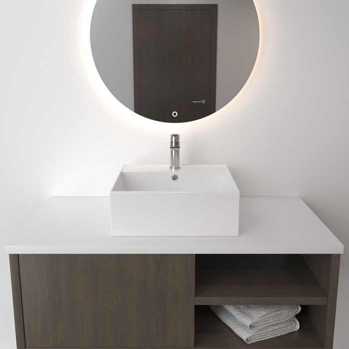 Un baño con un lavabo cuadrado y un espejo redondo.