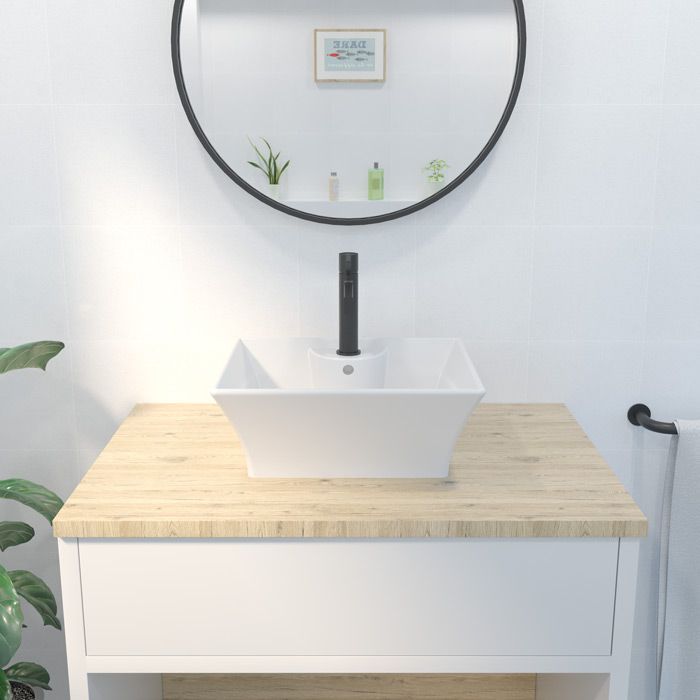 Un baño con un lavabo cuadrado y un espejo redondo.