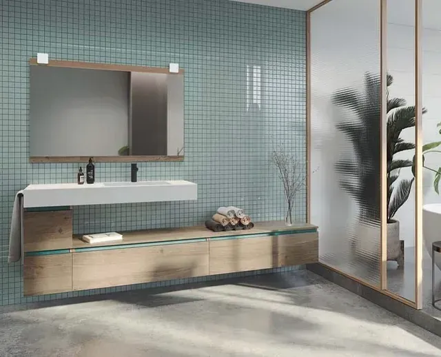 Un baño con lavabo, espejo y planta.