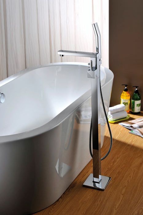 Una bañera está colocada sobre un suelo de madera al lado de una ventana.