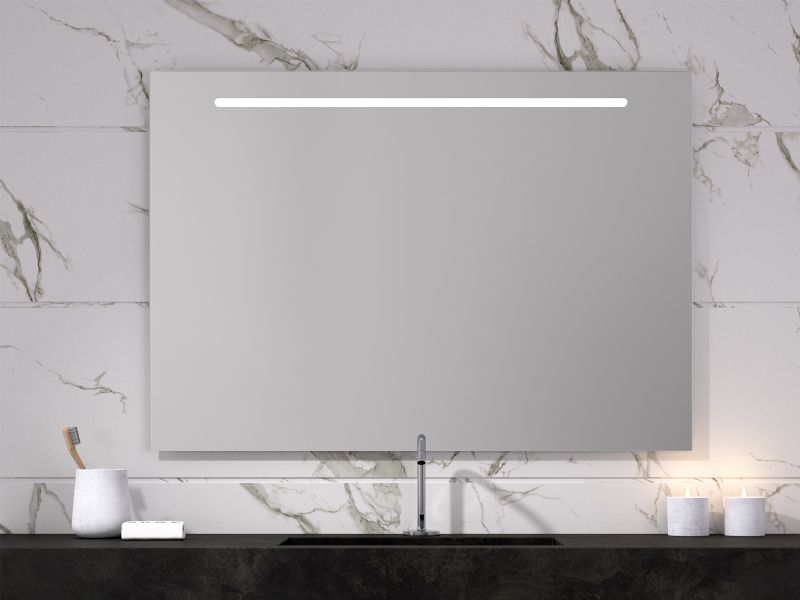 Un espejo de baño está colgado en una pared de mármol encima de un lavabo.