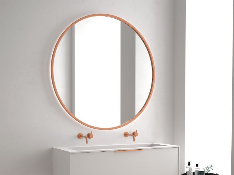 Un baño con un espejo redondo y un lavabo.