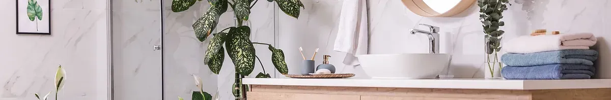 Un baño con lavabo, espejo y planta.