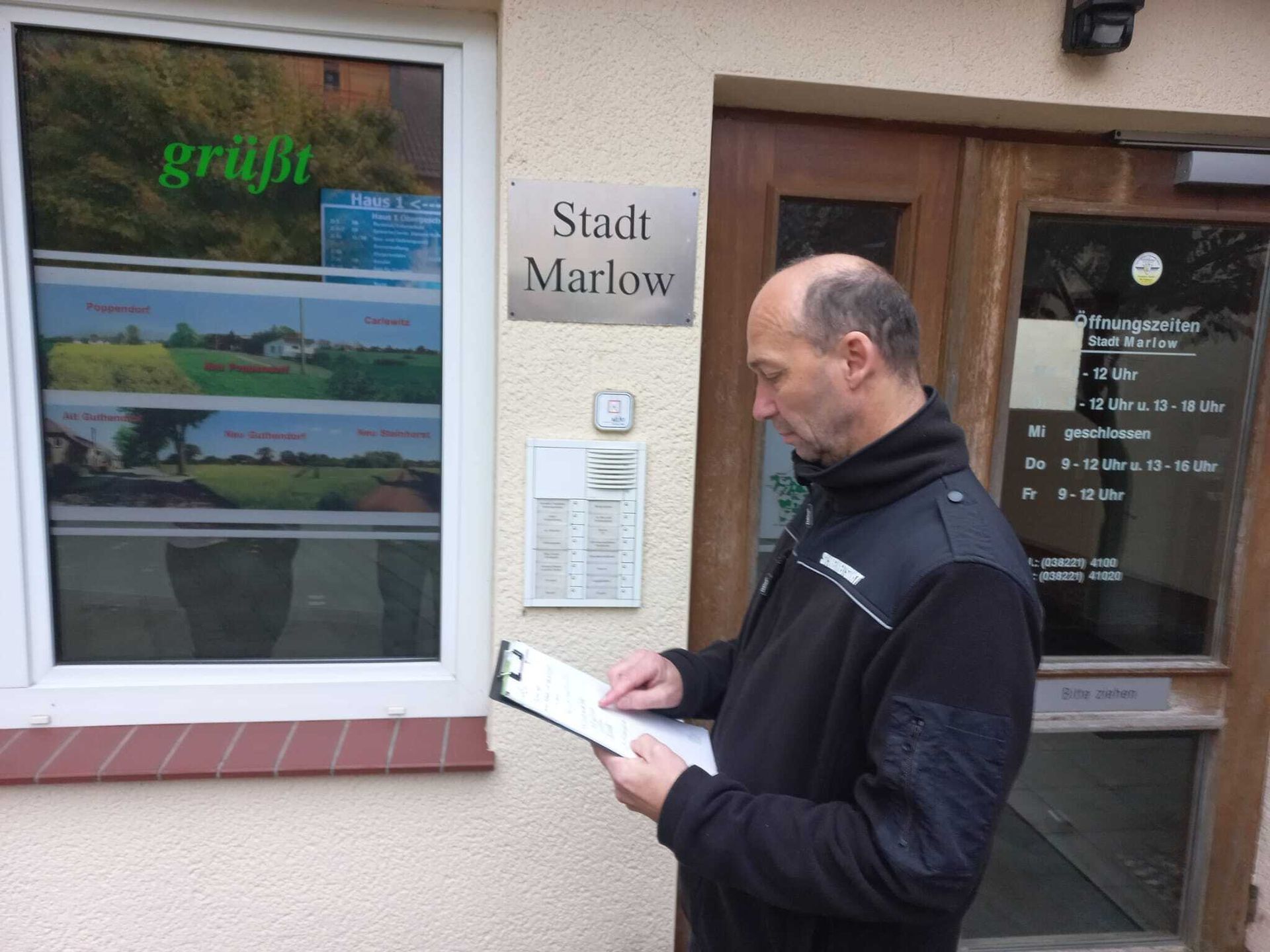 Ein Mann steht vor einem Gebäude mit der Aufschrift „Stadt Marlow“