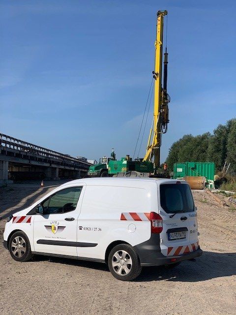 Ein weißer Lieferwagen steht vor einem Baukran.